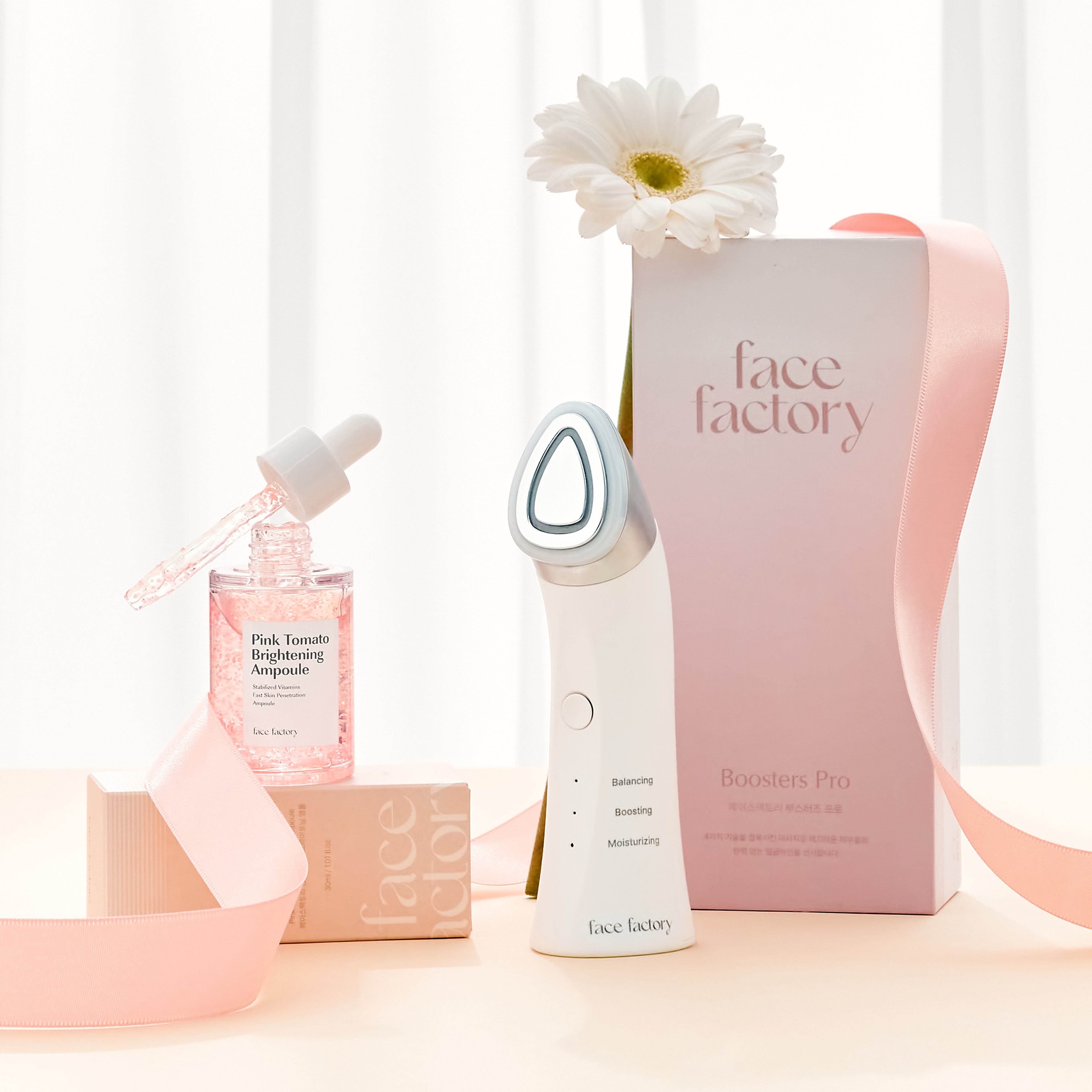 Boosters Pro facial device displayed with Pink Tomato Brightening Ampoule and packaging