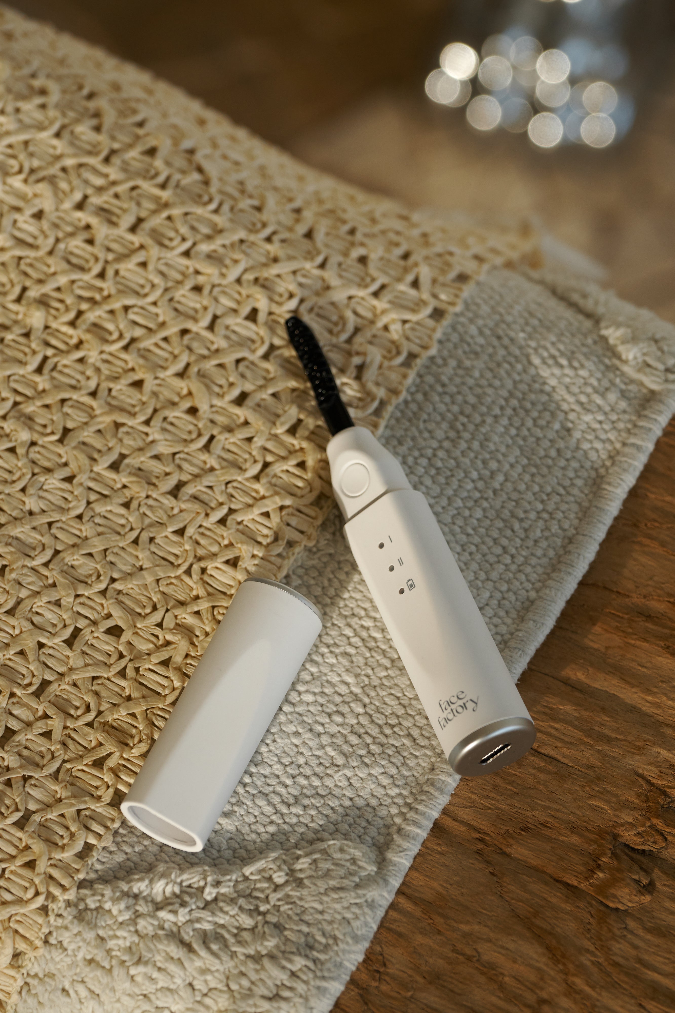 Face Factory's Eyelash Styler 2.0 with a black brush attachment on a textured surface