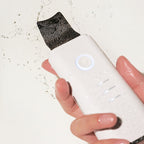 Galvanic Z-Water Peeling facial device held in hand with 24k gold plated spatula tip and water splashes